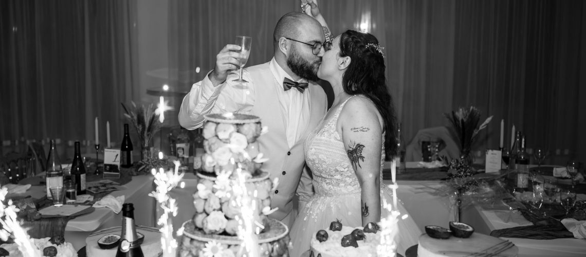 bisou des mariés devant le gâteau de mariage